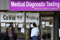 Exam Corp Lab employee, right, wears a mask as she talks with a patient lined up for COVID-19 testing in Niles, Ill., Wednesday, Oct. 21, 2020. (AP Photo/Nam Y. Huh)