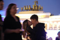 School graduates kiss at the Palace Square as they take part the Scarlet Sails festivities marking school graduation in St. Petersburg, Russia, early Saturday, June 25, 2022. The Scarlet Sails celebration is a rite of passage both figuratively and literally. Every year, tall ships with glowing red sails make their way down the Neva River in St. Petersburg to honor recent school graduates as they set out on the journey into adulthood. (AP Photo/Dmitri Lovetsky)
