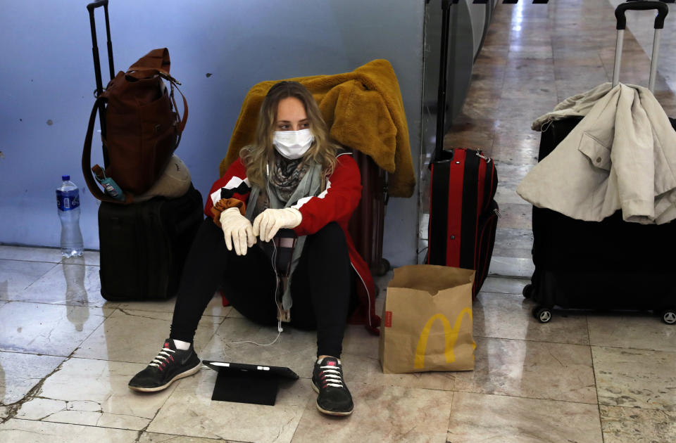 Una viajera lleva una mascarilla y guantes como precaución contra el nuevo coronavirus en el aeropuerto internacional Benito Juárez en Ciudad de México el miércoles 25 de marzo de 2020. (AP Foto/Marco Ugarte)