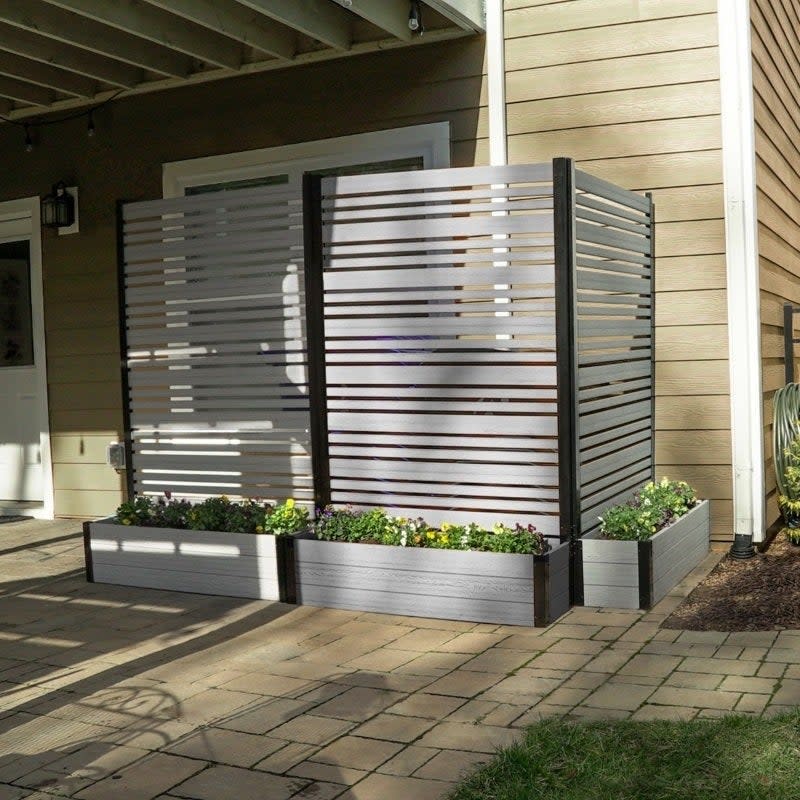 Outdoor privacy screen with horizontal slats and integrated planter boxes at the base, positioned on a patio