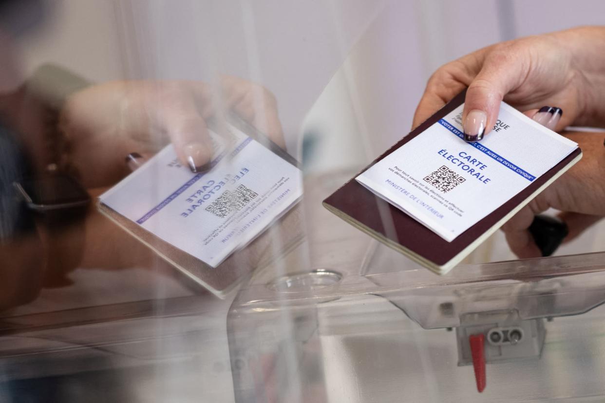 Une électrice présente sa carte électorale et son passeport, dimanche 24 avril 2022, à l'occasion du second tour de l'élection présidentielle à Bouée, en Loire-Atlantique - Loïc Venance - AFP