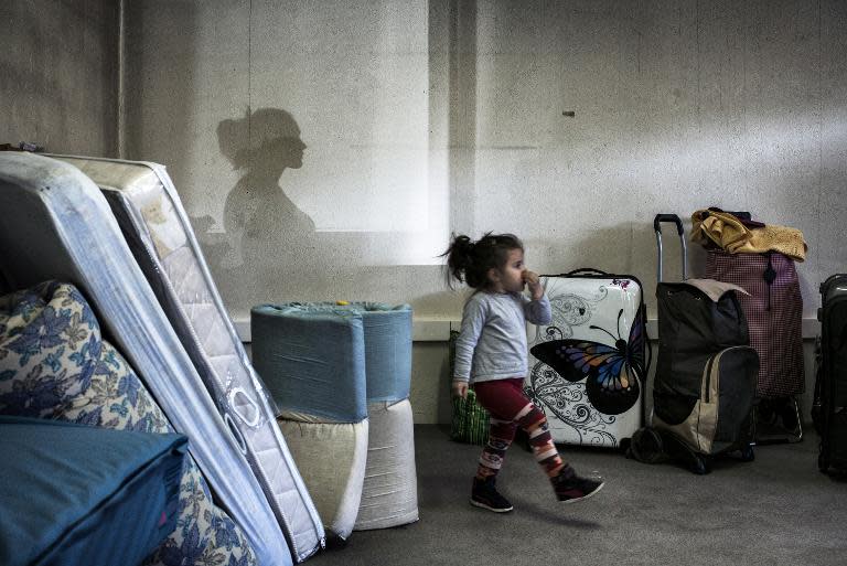 A girl walks amongst bags and mattresses as Eastern European migrants wait to temporarily settle in a locale in Decines after staying in buildings belonging to the army and the diocese of Lyon, on April 21, 2015