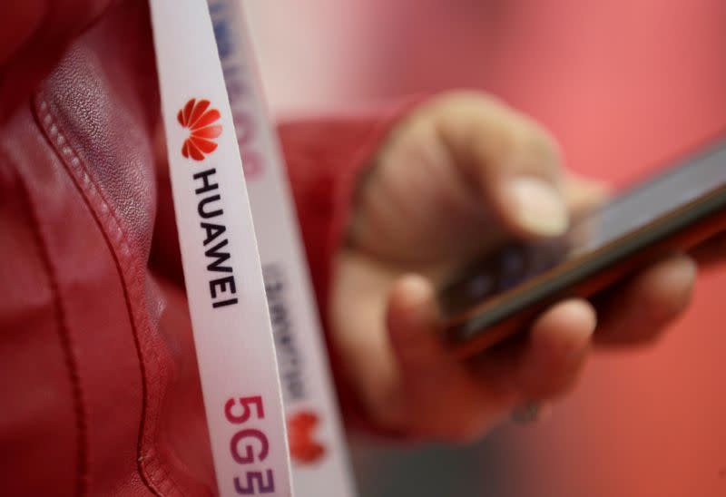 FILE PHOTO: An attendee wears a badge strip with the logo of Huawei and a sign for 5G at the World 5G Exhibition in Beijing