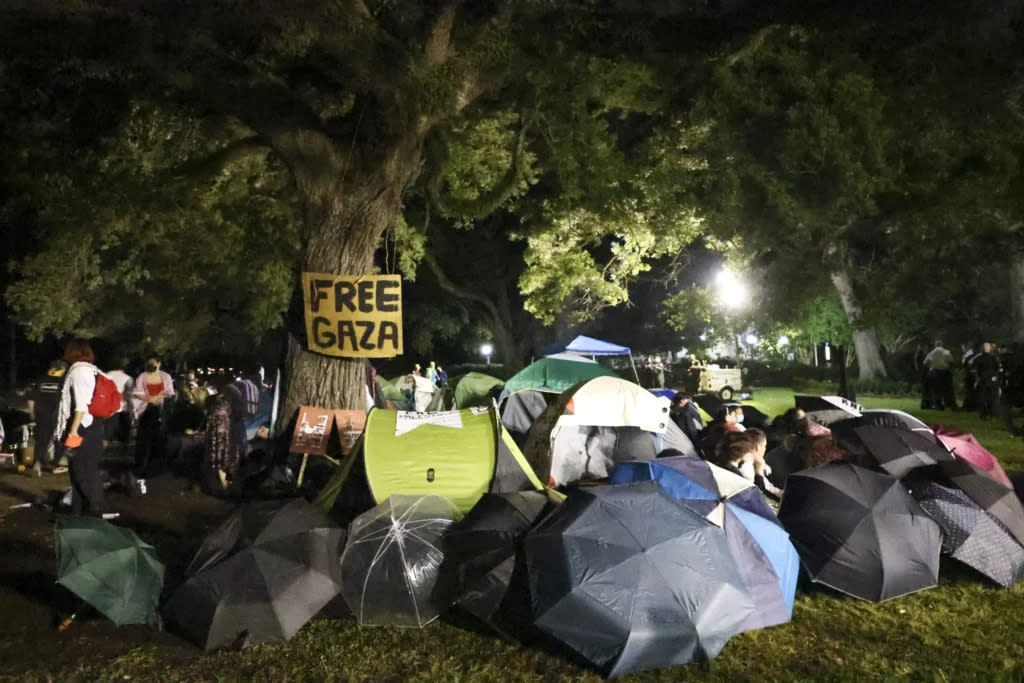 Protestors stand near an encampment on the Tulane University campus. A sign is posted on a tree that reads: Free Gaza.