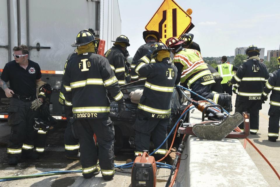 In this image taken Sunday, July 14, 2019, and provided by the Indianapolis Fire Department, emergency personnel work at the scene of fatal crash along Interstate 465 in Indianapolis. Authorities say a woman and her 18-month-old twin daughters died in the fiery, seven-vehicle crash on an Indianapolis freeway. (Battalion Chief Rita L. Reith/Indianapolis Fire Department via AP)