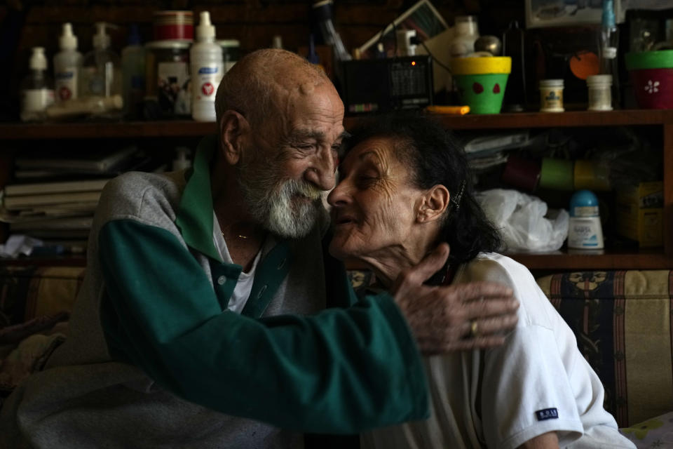 Marie Orfali, 76, and her husband Raymond, share a moment in their apartment in Beirut, Lebanon, Tuesday, June 15, 2021. Tiny and bowed by age, Orfali makes the trip five times a week from her Beirut apartment to the local church, a charity and a nearby soup kitchen to fetch a cooked meal for her and her 84-year-old husband. (AP Photo/Hassan Ammar)