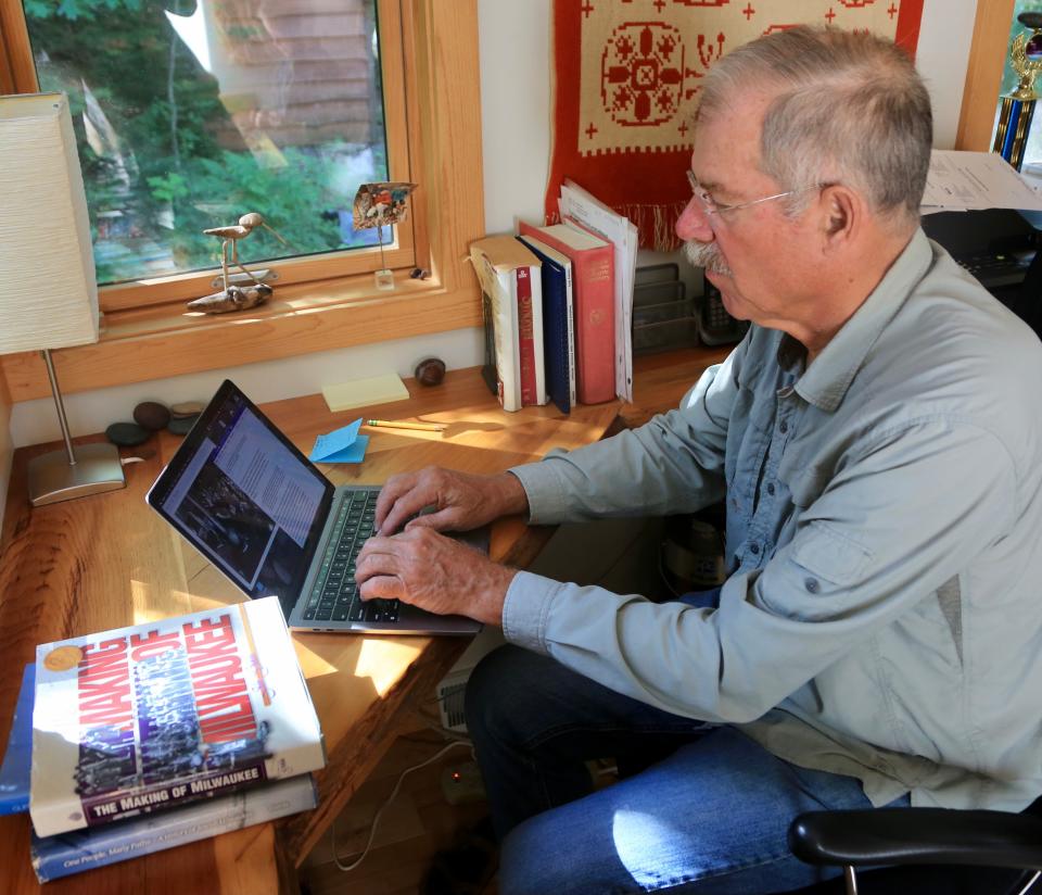 Local historian John Gurda is shown working on his laptop on Aug. 11, 2022. Gurda is the author of "The Making of Milwaukee," seen in the foreground of the image, a book about the history of Milwaukee.