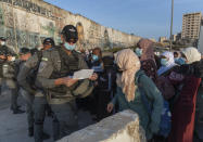 Palestinian women wait to cross the Qalandia checkpoint between the West Bank city of Ramallah and Jerusalem, to attend the first Friday prayers in al-Aqsa mosque, during the Muslim holy month of Ramadan, Friday, April 16, 2021. A limited number of Palestinian residents who carry both a travel permit and a vaccination document, are allowed to cross into Israel to attend the prayers at al-Aqsa mosque, due to the coronavirus pandemic. (AP Photo/Nasser Nasser)