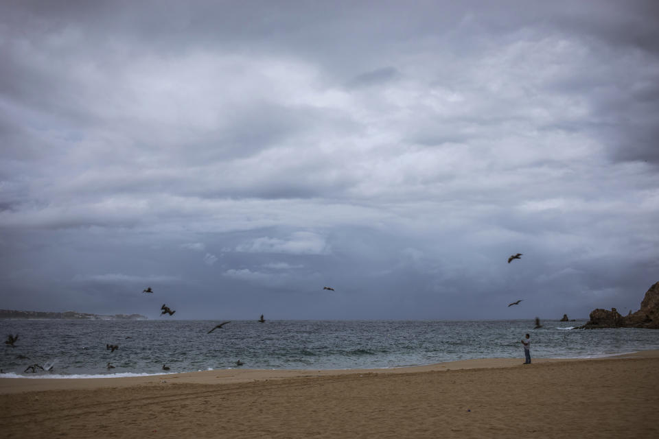 A tourist walks on the beach before the expected arrival of Hurricane Lorena, in Los Cabos, Mexico, Friday, Sept. 20, 2019. Hurricane Lorena neared Mexico's resort-studded Los Cabos area Friday as owners pulled their boats from the water, tourists hunkered down in hotels, and police and soldiers went through low-lying, low-income neighborhoods urging people to evacuate. (AP Photo/Fernando Castillo)