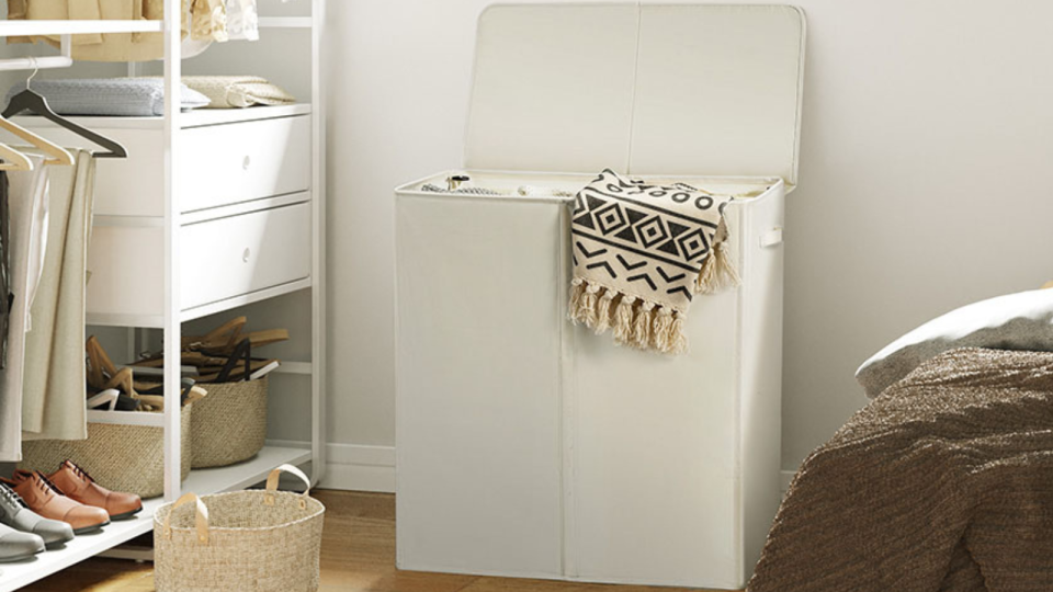 The beige double-sided laundry basket in a bedroom