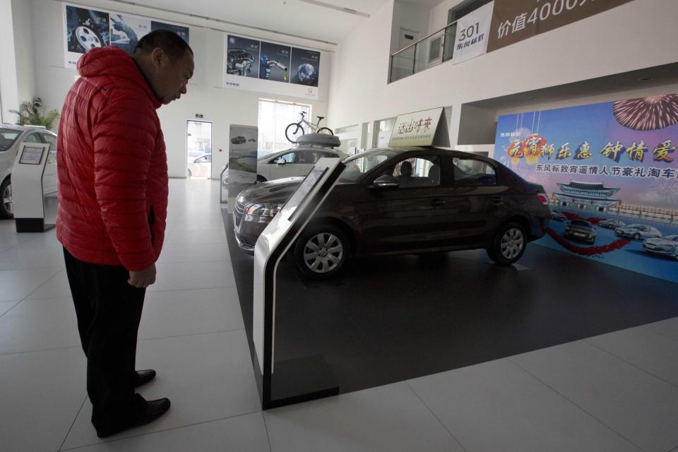 A customer looks at a Peugeot car on display at a Dongfeng and Peugeot joint venture show room in Beijing Wednesday, Feb. 19, 2014. Loss-making French carmaker PSA Peugeot Citroen is getting a 3 billion euro lifeline backed by Chinese investors and the French government in a deal that will see the company's founding family hand over control after more than two centuries at the helm. Chinese automaker Dongfeng and the French government are each investing 800 million euros ($1.1 billion) in Peugeot, throwing a financial lifeline to the struggling French auto brand and possibly expanding its global presence. (AP Photo/Ng Han Guan)