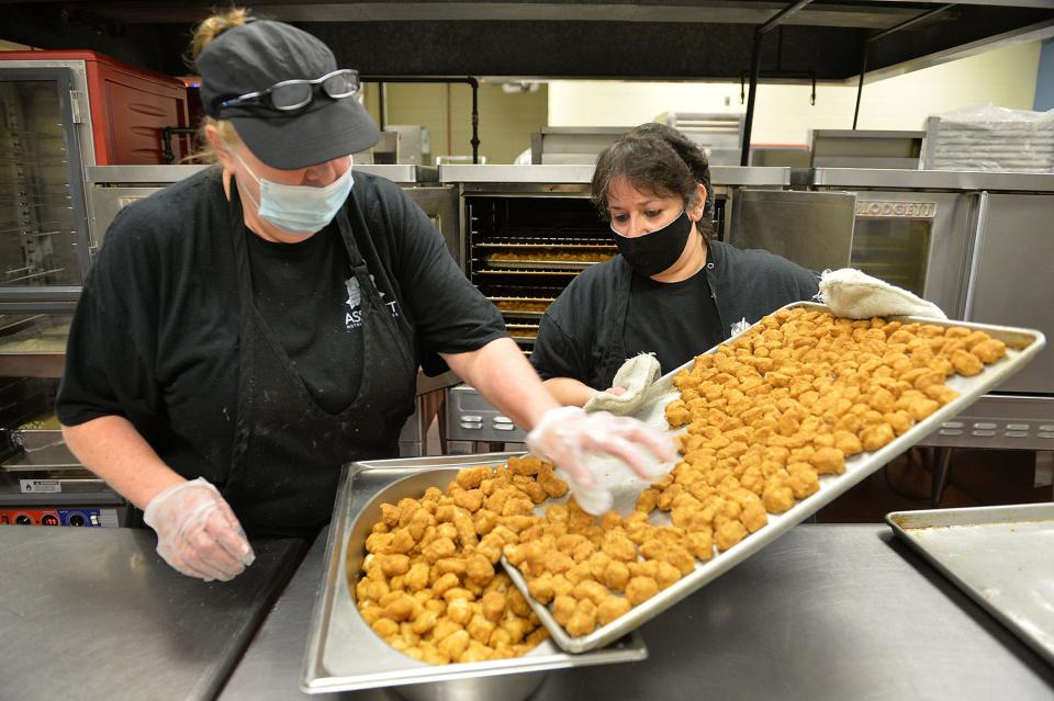 Maureen Drohan, left, and Carol DeMeo, cafeteria workers at Assabet Valley Regional Technical High School in Marlborough, prepare popcorn chicken for students.