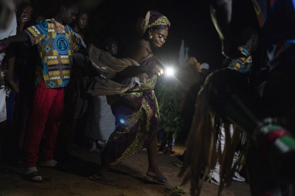 A woman dances to the rhythm of the Mandinka drums during the Kankurang ritual in Bakau, Gambia, Saturday, Oct. 2, 2021. The ritual is associated with circumcision and initiatory rites. (AP Photo/Leo Correa)