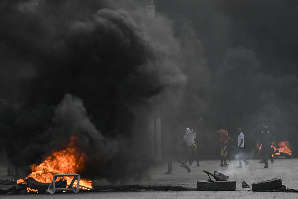 Protesters demanding justice for the assassinated President Jovenel Moise stand between burning barricades in Cap-Haitien, Haiti, Thursday, July 22, 2021. Demonstrations after a memorial service for Moise turned violent on Thursday afternoon with protesters shooting into the air, throwing rocks and overturning heavy concrete barricades next to the seashore as businesses closed and people took cover. (AP Photo/Matias Delacroix)