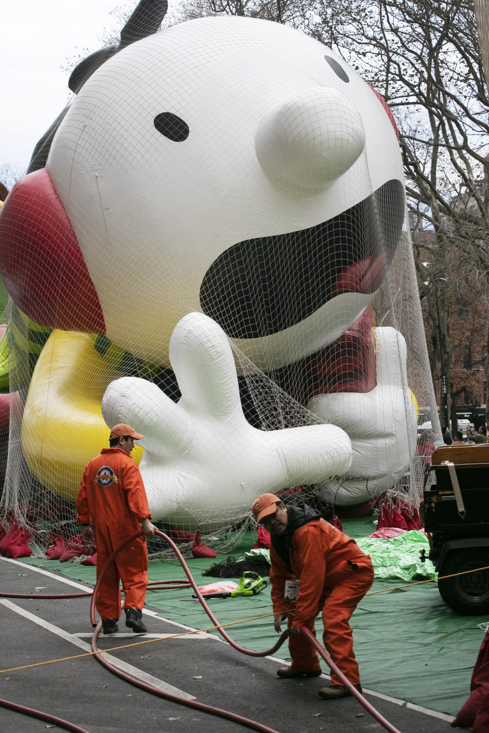 Workers carry a helium hose as the Diary of a Wimpy Kid balloon is inflated, Wednesday, Nov. 27, 2019 in New York. The city's big Macy's Thanksgiving Day Parade on Thursday will take place amid strong winds that could potentially ground the giant character balloons. (AP Photo/Mark Lennihan)