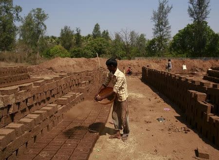 A labourer throws mud on bricks kept for drying at a kiln in Karjat, India, March 10, 2016. REUTERS/Danish Siddiqui