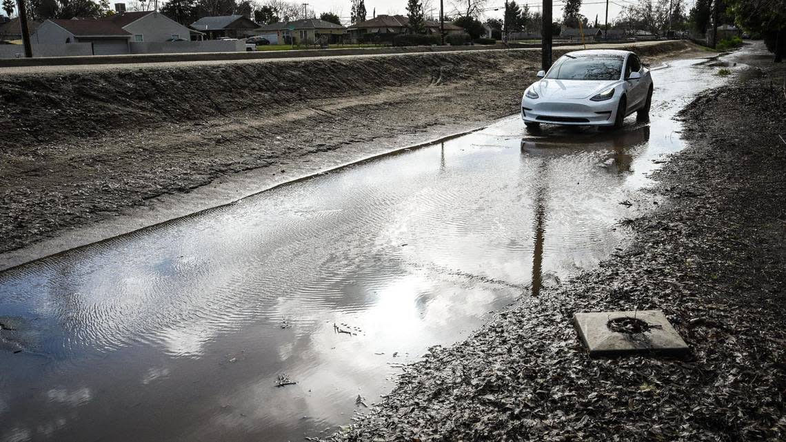 A car pauses before driving through flood water on James Lane near Maroa in central Fresno following a “bomb cyclone” storm that blew through the Central Valley, on Thursday, Jan. 5, 2023.