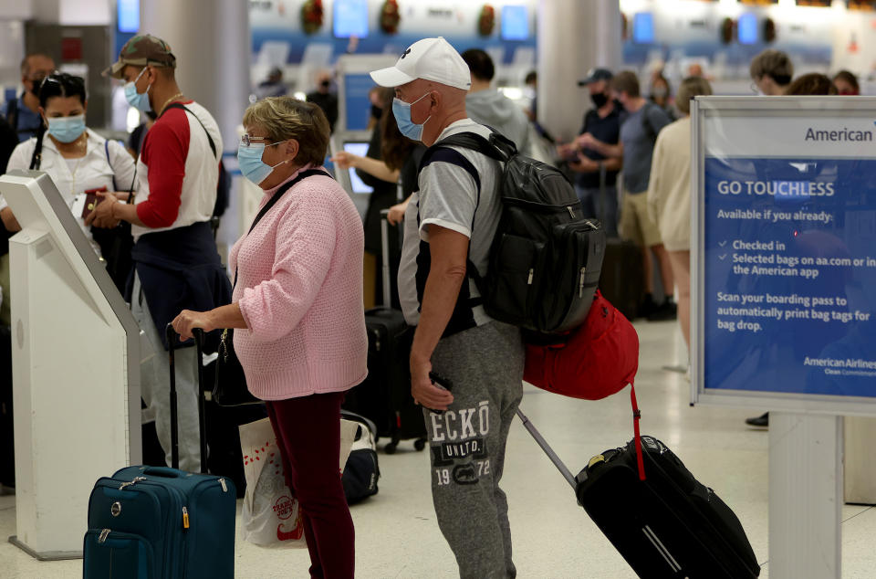 MIAMI, FLORIDA - DECEMBER 28:  Travelers make their way through Miami International Airport on December 28, 2021 in Miami, Florida. Over the holiday weekend, COVID-19 cases in the U.S. reached their highest level in nearly a year. More than 2,000 flights were canceled over the weekend as airlines dealt with a surge in COVID-19 cases due to the Omicron variant. (Photo by Joe Raedle/Getty Images)