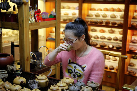 An owner of a family tea-ware shop drinks tea as handmade red clay pots are seen in the background, in Dingshu town, Yixing city, known as "pottery city", Zhejiang province, China November 14, 2017. REUTERS/Christian Shepherd