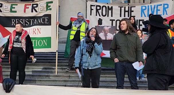 Natalie Knight, center, holding microphone, is facing criticism and calls to be fired from her academic job after a speech she gave at a pro-Palestinian rally in late October. Knight is defending her comments as legitimate speech in the face of Israeli actions against Palestinians.
