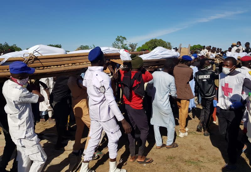 Men carry the bodies of people killed by militant attack, during a mass burial in Zabarmari