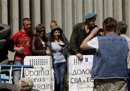 People take photos with pro-Russian protesters in front of the seized office of the SBU state security service in Luhansk, eastern Ukraine April 25, 2014. REUTERS/Vasily Fedosenko