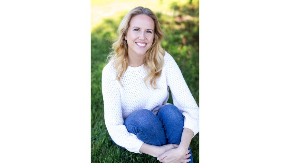 blonde woman in a jumper sitting on grass