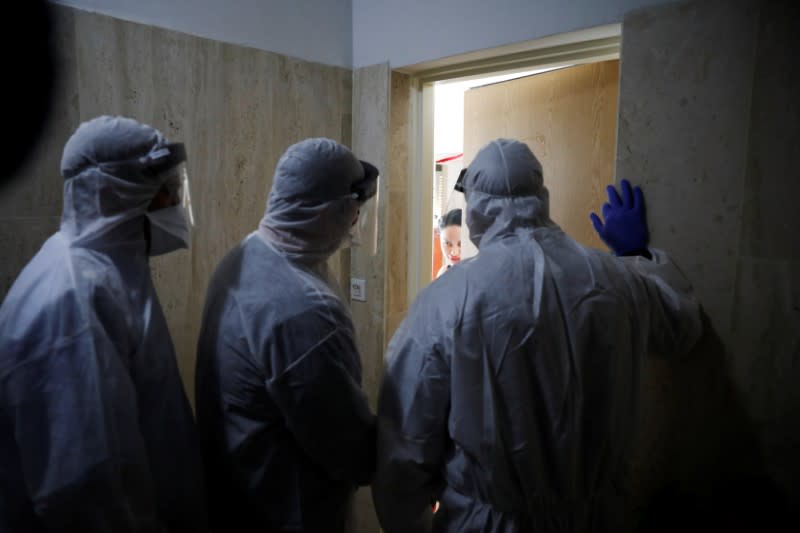 Health Ministry inspectors speak with a woman who is in self quarantine as a precaution against coronavirus spread in Hadera