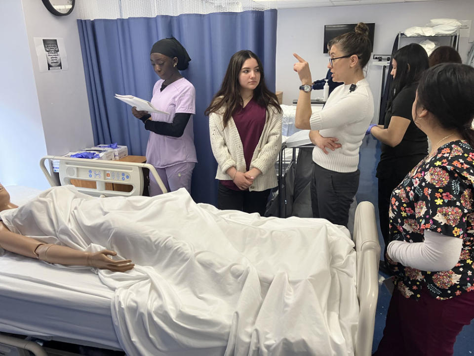 As Aminata Diop (left) studies care instructions, Abigail Vitale (center) and Crisla Quixan (right) listen as instructor Wendy Reynoso talks about an upcoming certified nursing exam. (Greg Toppo)