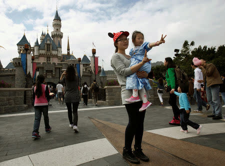 Mainland Chinese visitors pose in front of a castle at Hong Kong Disneyland, China February 18, 2013. REUTERS/Bobby Yip/File Photo