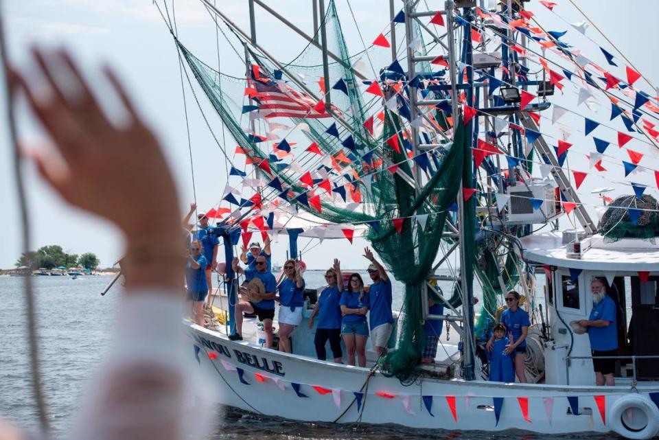 People on a boat wave to Msgr. Dominick Fullam and the Shrimp King and Queen as they receive a blessing during the Blessing of the Fleet in Biloxi on Sunday, May 28, 2023.