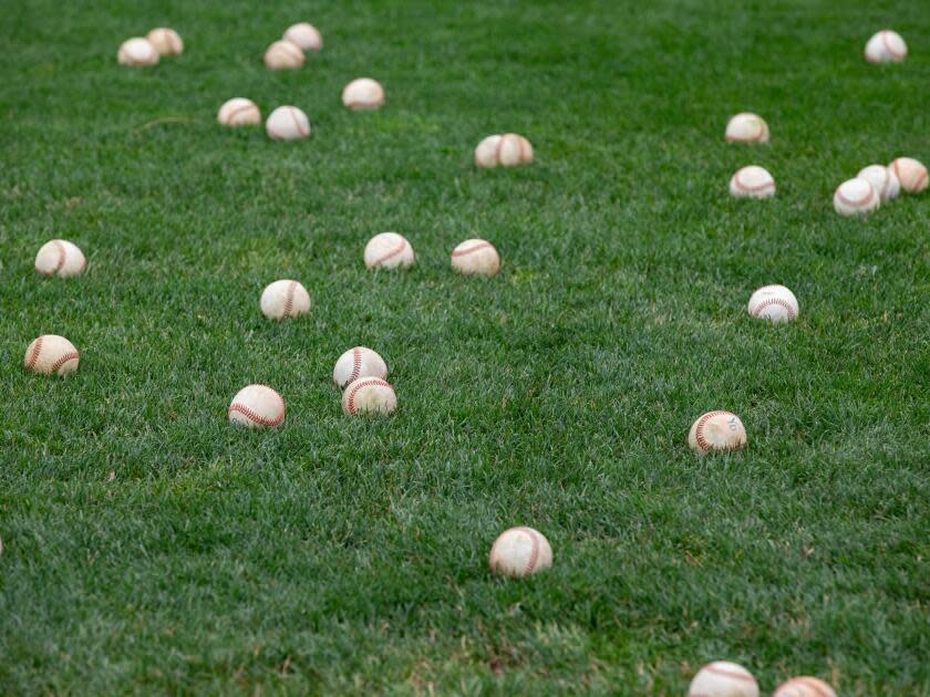  Baseballs lay on the grass during a practice.