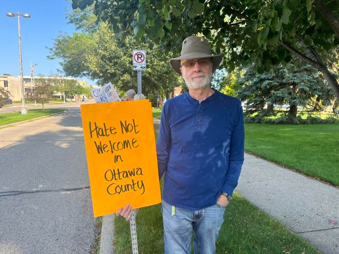 A protestor holds a sign in Grand Haven on Wednesday, July 19.