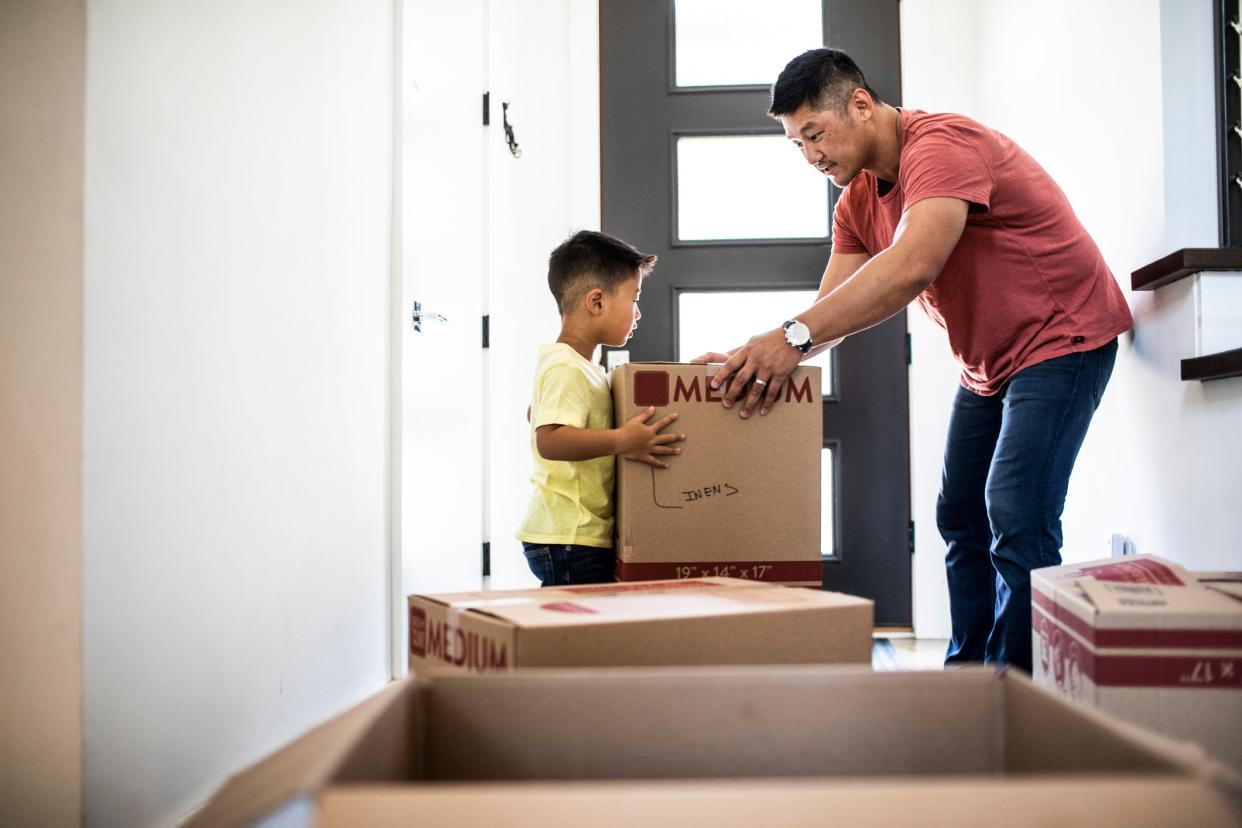 Father and son lifting moving boxes at new home. (Getty Images)