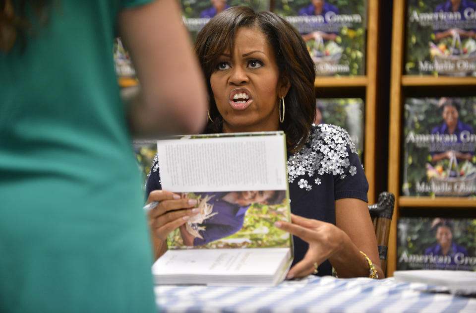 US First Lady Michelle Obama signs a copy of her book 'American Grown: The Story of the White House Kitchen Garden and Gardens Across America,' during a book signing event at Politics & Prose in Washington, DC, on May 7, 2013. Photo credit:  JEWEL SAMAD/AFP/Getty Images