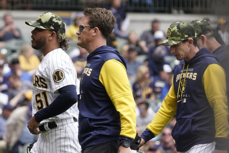 Milwaukee Brewers starting pitcher Freddy Peralta leaves the game with a trainer during the fourth inning of a baseball game against the Washington Nationals Sunday, May 22, 2022, in Milwaukee. (AP Photo/Morry Gash)