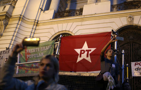 People take photos in front of a banner of Worker Party (PT) during a protest against the conviction on corruption charges of former president Luiz Inacio Lula da Silva, in Rio de Janeiro, Brazil July 20, 2017. REUTERS/Pilar Olivares