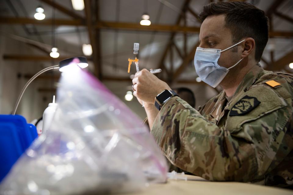 Oregon Army National Guard Spc. Toby Sewell draws up doses of vaccines for the COVID-19 vaccination site at the Oregon State Fairgrounds.