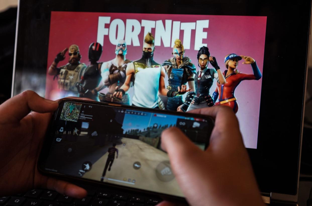 Google Makassar, South Sulawesi, Indonesia. 15th Aug, 2020. A child is playing a game on a cellphone with a picture of the Fortnite game on the computer screen in the background. Apple and Google announced their decision to remove Fortnite games from the App Store and Google Play app stores. Credit: Herwin Bahar/ZUMA Wire/Alamy Live News