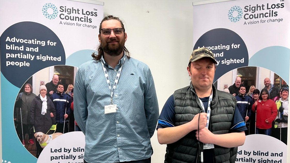 Tyne and Wear Sight Loss Council volunteers Jack Moffat and Matty Bolam standing in front of two banners