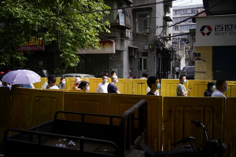 Residents wearing face masks line up for nucleic acid testings at a residential compound in Wuhan