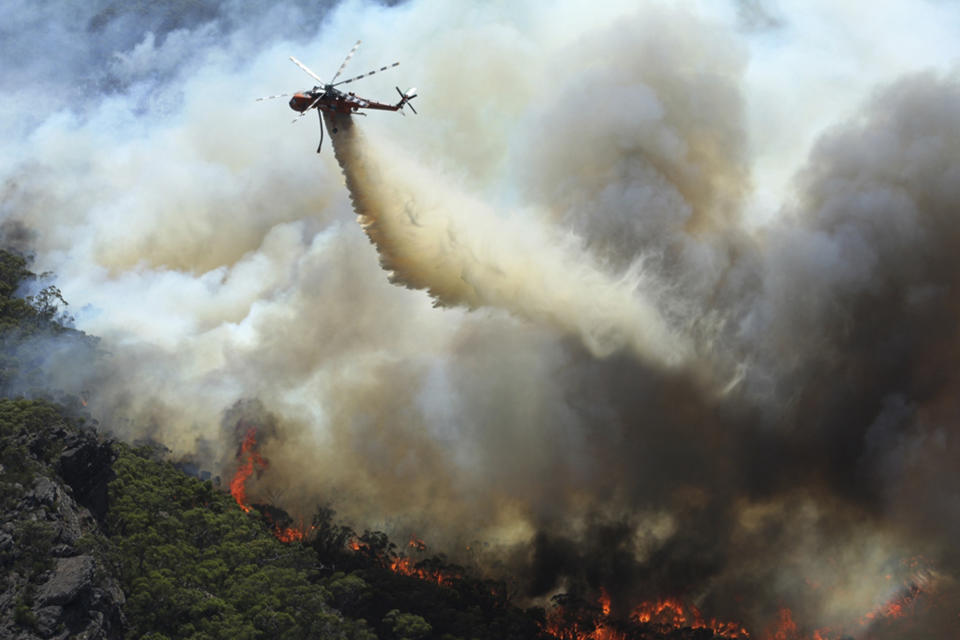 In this Thursday, Jan. 16, 2014 photo released by Victoria Country Fire Authority, a water bomber works over a large fire burning throughout Victoria's Grampians region. Fire authorities in Victoria said there are 68 fires burning at present with stronger winds expected for Friday afternoon, urging residents in these affected regions to evacuate. (AP Photo/Country Fire Authority)