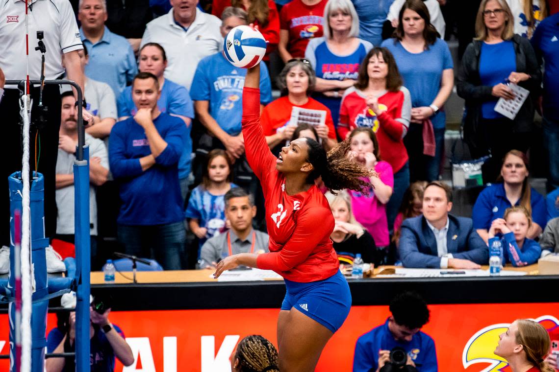 London Davis (21) of the Kansas volleyball team hits the ball while athletic director Travis Goff (seated) looks on during a match between KU and K-State at Horejsi Family Athletics Center in Lawrence, Kan.