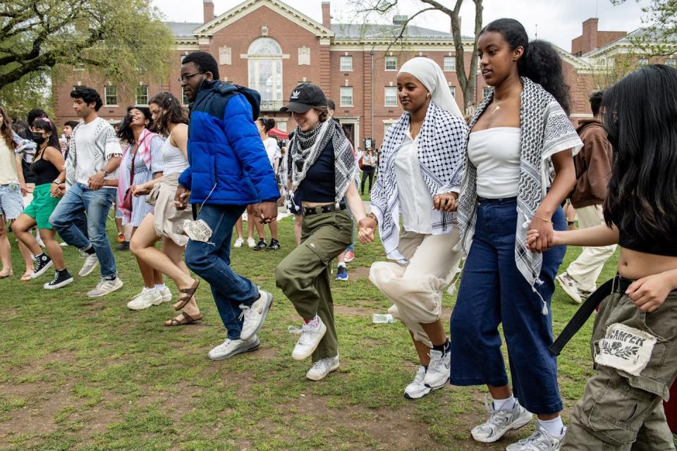 People hold hands in a line and dance.