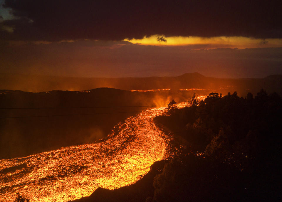 FILE- Lava flows as volcano continues to erupt on the Canary island of La Palma, Spain, on Nov. 29, 2021. Authorities on a Spanish island are declaring a volcanic eruption that has caused widespread damage but no casualties officially finished, following ten days of no significant sulfur dioxide emissions, lava flows or seismic activity. But the emergency in La Palma, the northwesternmost of the Atlantic Ocean's Canary Islands, is not over yet, said the director of the archipelago’s volcanic emergency committee, or Pevolca, Julio Pérez. (AP Photo/Emilio Morenatti, File)