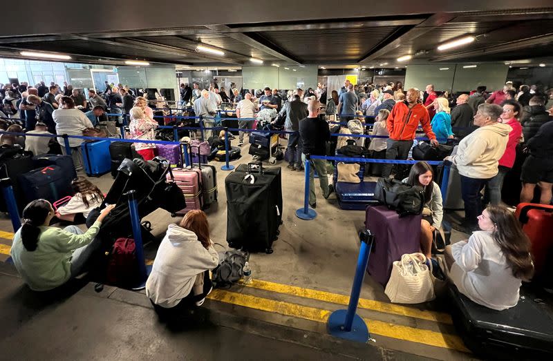 Passengers queue outside Terminal 1 after an overnight power cut led to disruptions and cancellations at Manchester Airport in Manchester