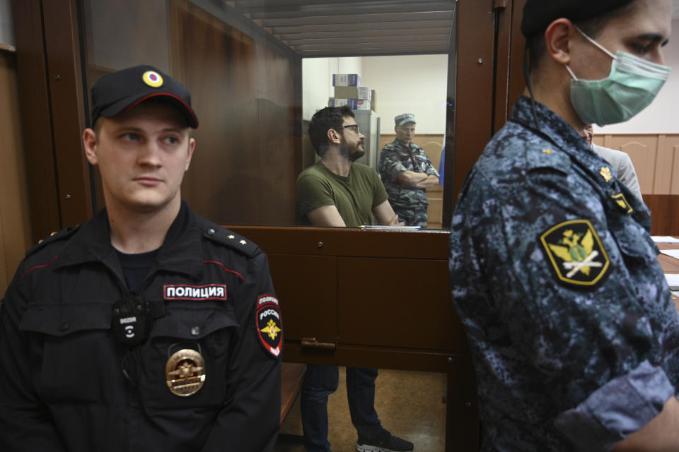 Russian opposition activist and a municipal deputy of the Krasnoselsky district Ilya Yashin stands in a cage at a court room during a hearing on his detention the Basmanny district court in Moscow, Russia, Wednesday, July 13, 2022. Yashin faces charges under a new law making it a crime to spread false information about the military that carry a potential sentence of up to 15 years in prison. (AP Photo/Dmitry Serebryakov)