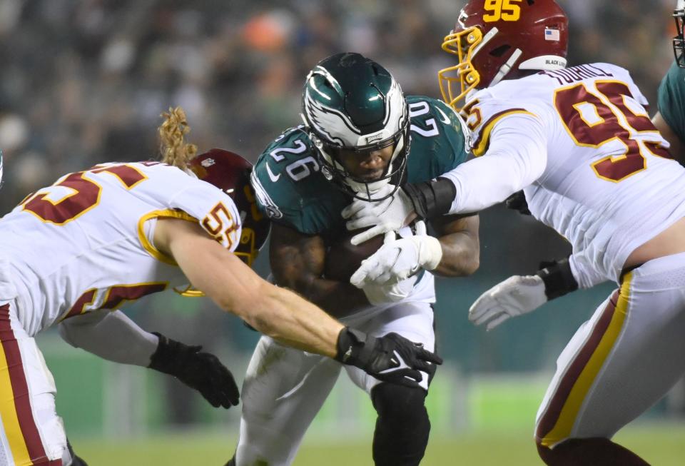 Philadelphia Eagles running back Miles Sanders is tackled by Washington Football Team outside linebacker Cole Holcomb (55) and defensive end Casey Toohill (95) during the second quarter at Lincoln Financial Field.