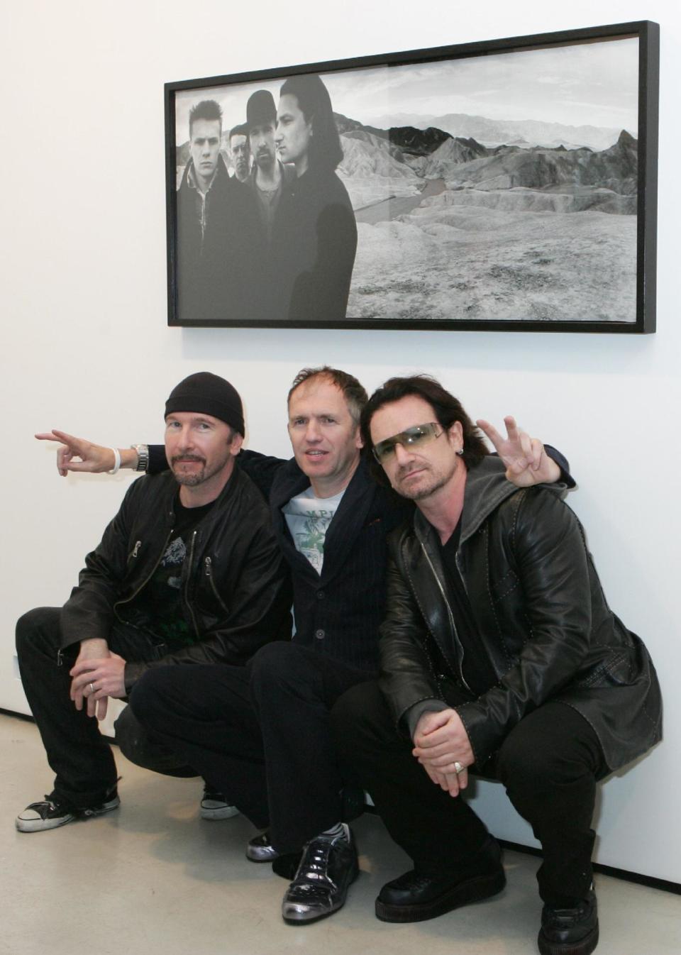 FILE - This Oct. 9, 2005 file photo shows U2's Bono, right, and guitarist The Edge, left, posing with photographer Anton Corbijn in New York, under a portrait of the band from the Joshua Tree album cover. The Library of Congress announces the sound recordings it has selected for long-term preservation in the National Recording Registry Wednesday April 2, 2014. (AP Photo/Diane Bondareff, File)