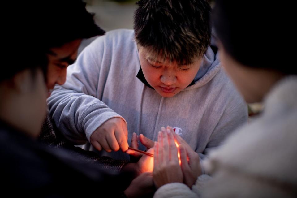 Mary Ma, center, lights incense with friends to honor her father.